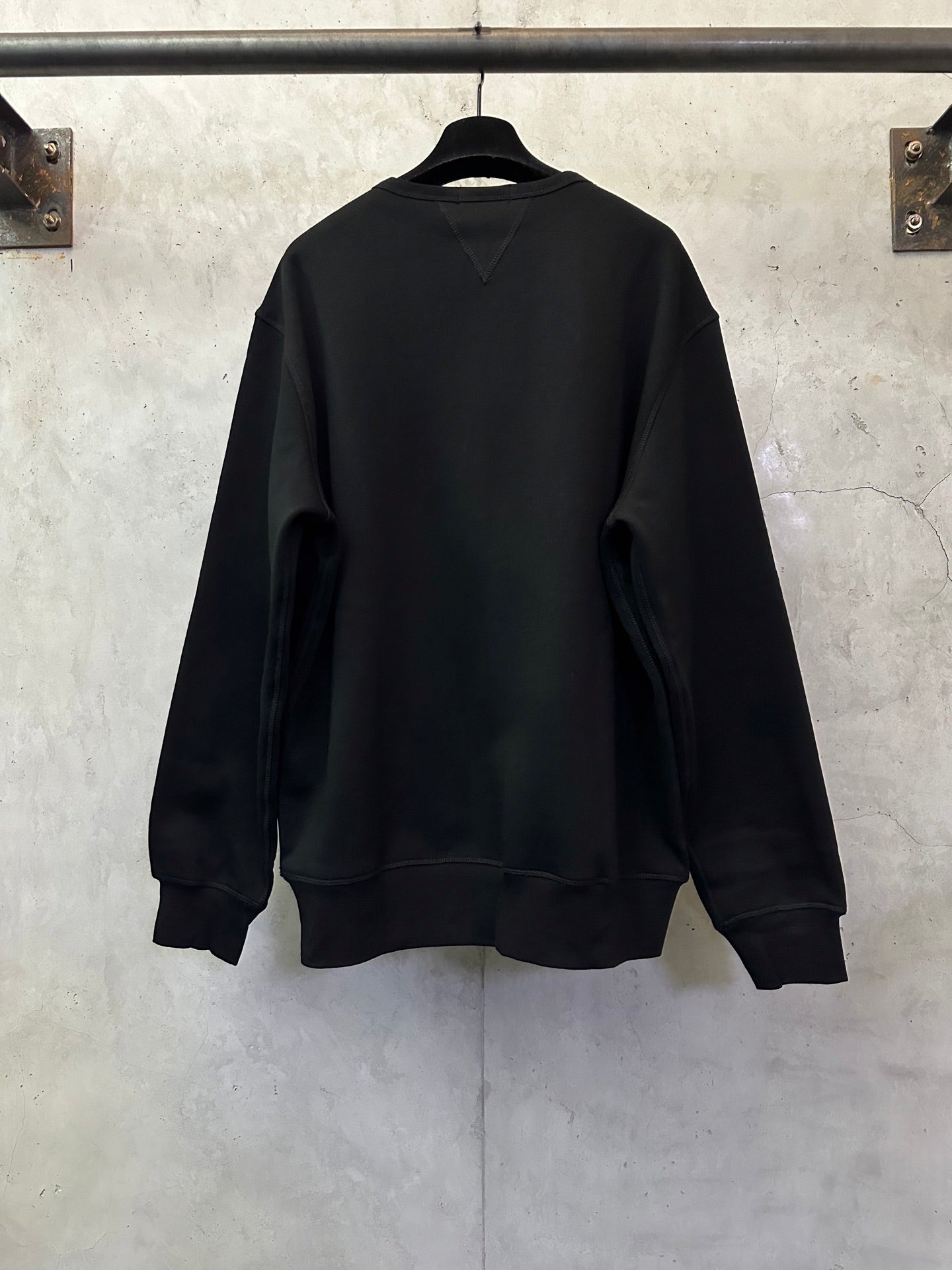 Black crewneck sweatshirt, back view with ribbed cuffs and hem