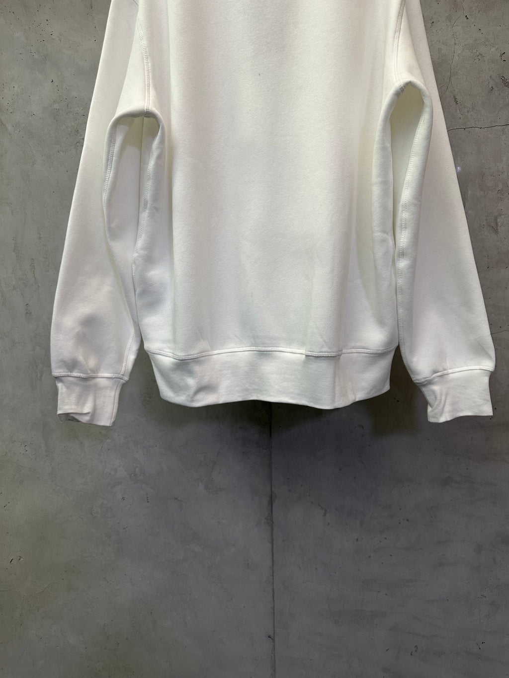 White crewneck sweatshirt, back view showing side hem and cuffs