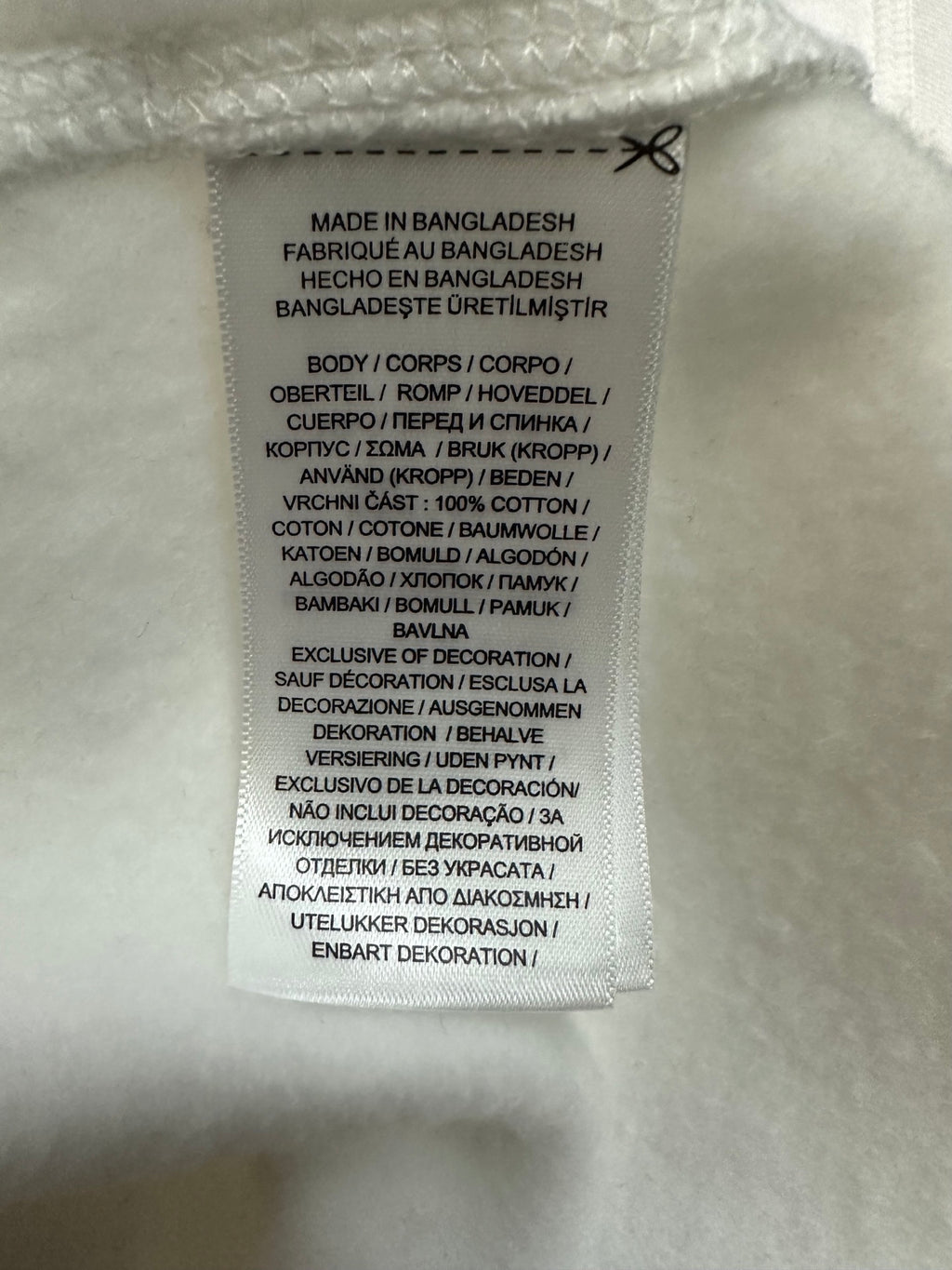 Interior clothing label with size and fabric details on white sweatshirt