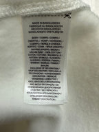 Interior clothing label with size and fabric details on white sweatshirt