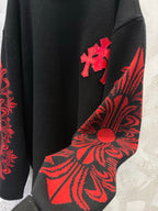 Black long-sleeve shirt sleeve with red floral swirl pattern and cross emblem