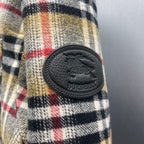 Burberry plaid fabric with oval leather logo patch and button accents