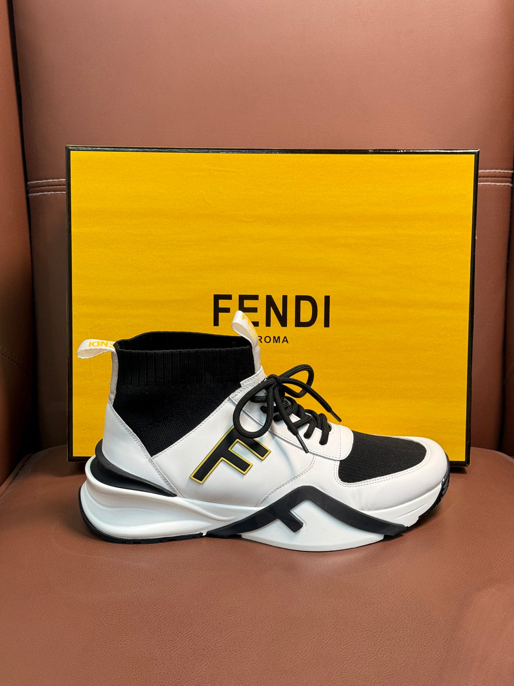 White and black high-top sneakers with black laces and side logo detail