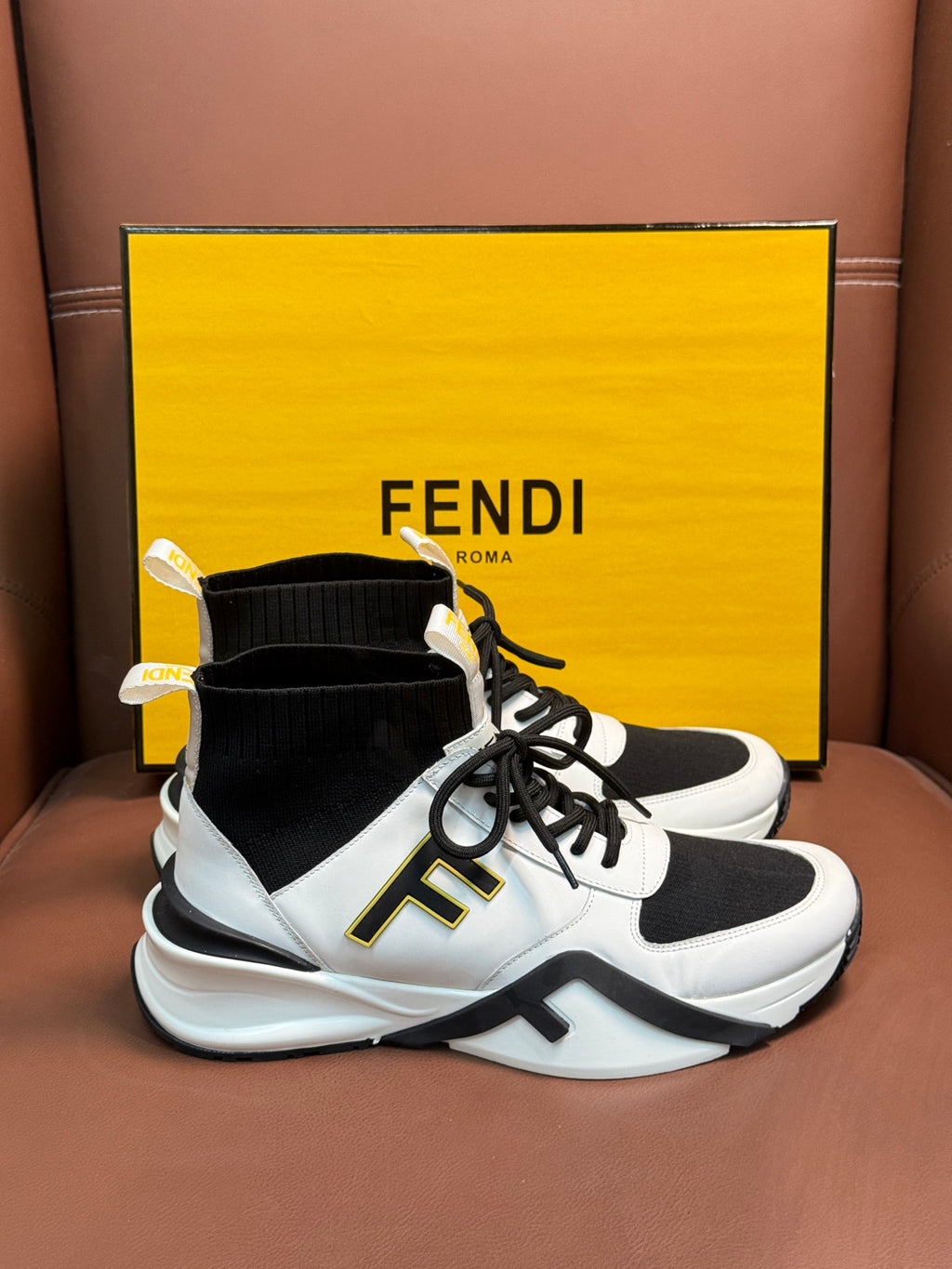 White and black high-top sneakers with black sock collar, laces, and thick sole