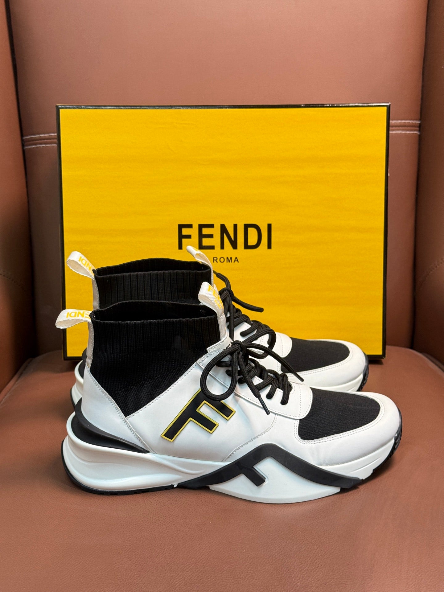 White and black high-top sneakers with black sock collar, laces, and thick sole