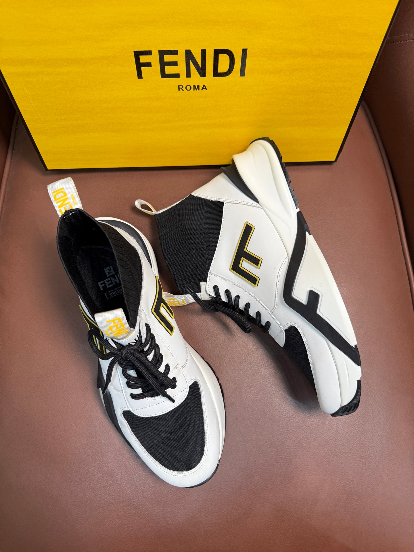 Pair of white and black high-top sneakers with black laces and bold side logo