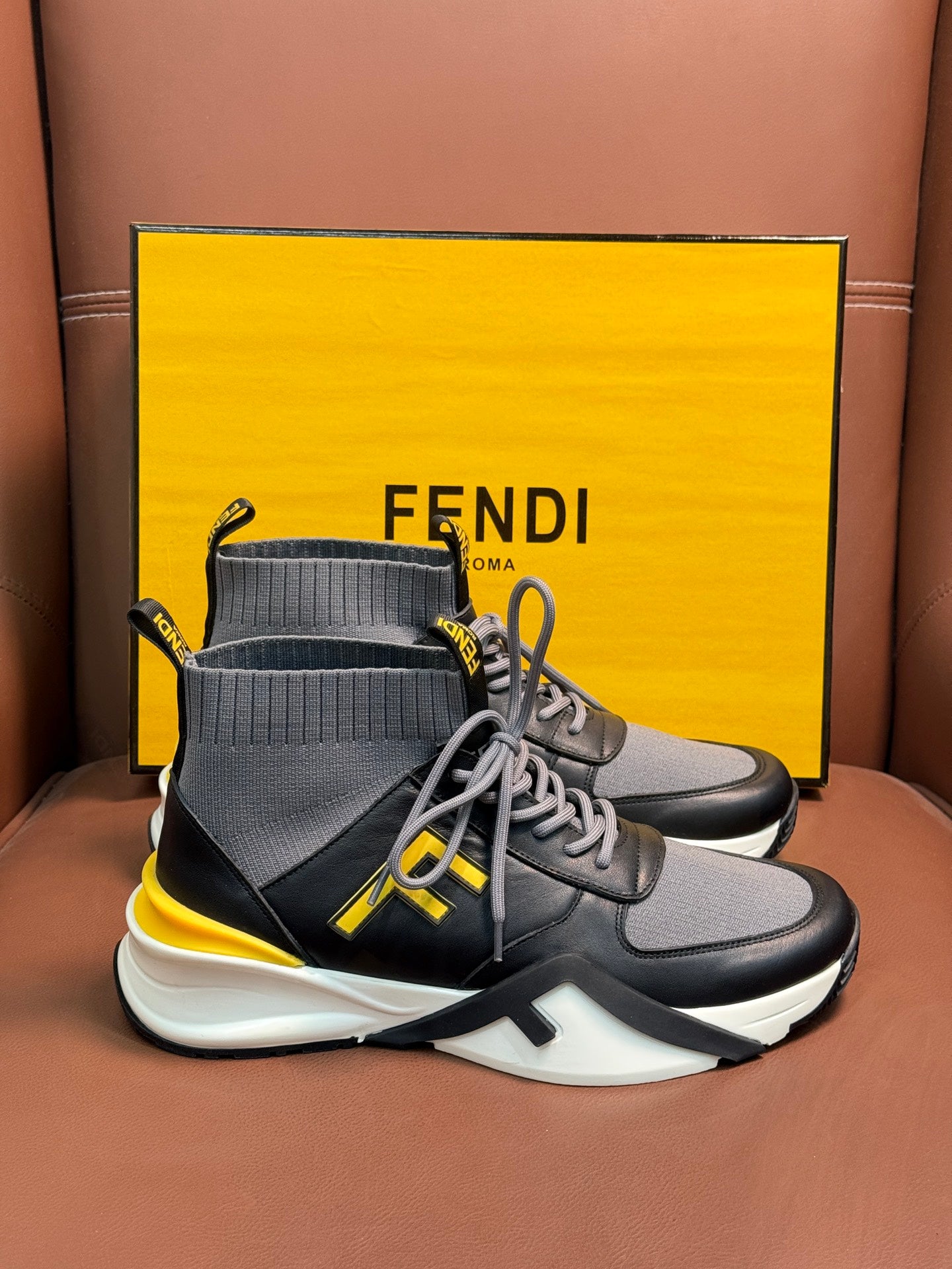 High-top sneakers with dark gray knit collar, gray laces, neon yellow logo detailing