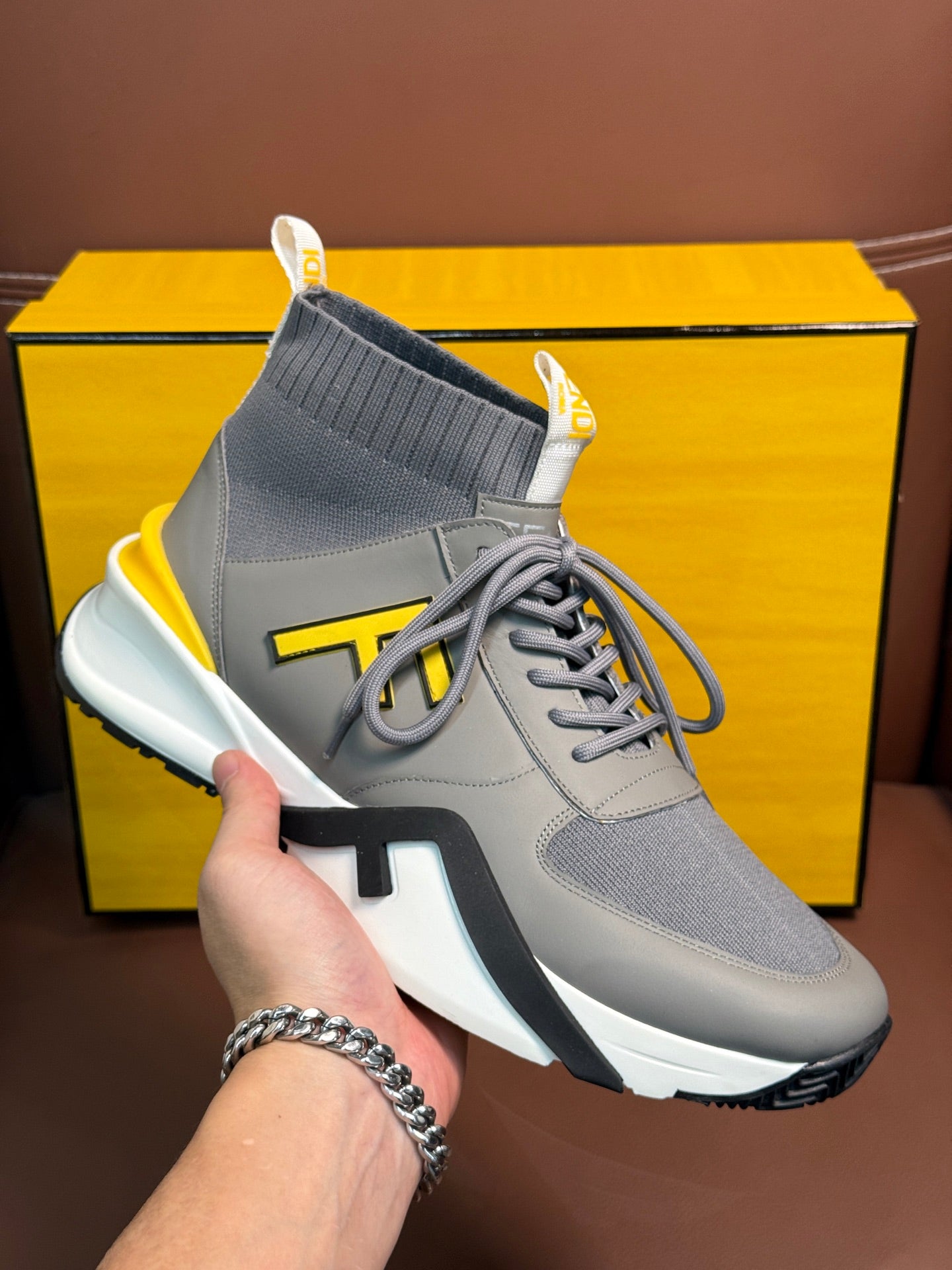 Single high-top sneaker close-up, light gray upper with neon yellow logo accents