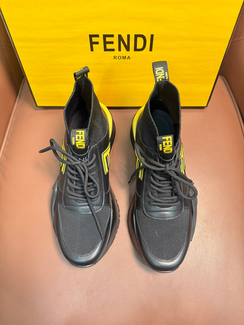 Pair of high-top sneakers in dark gray with neon yellow logo accents and chunky sole