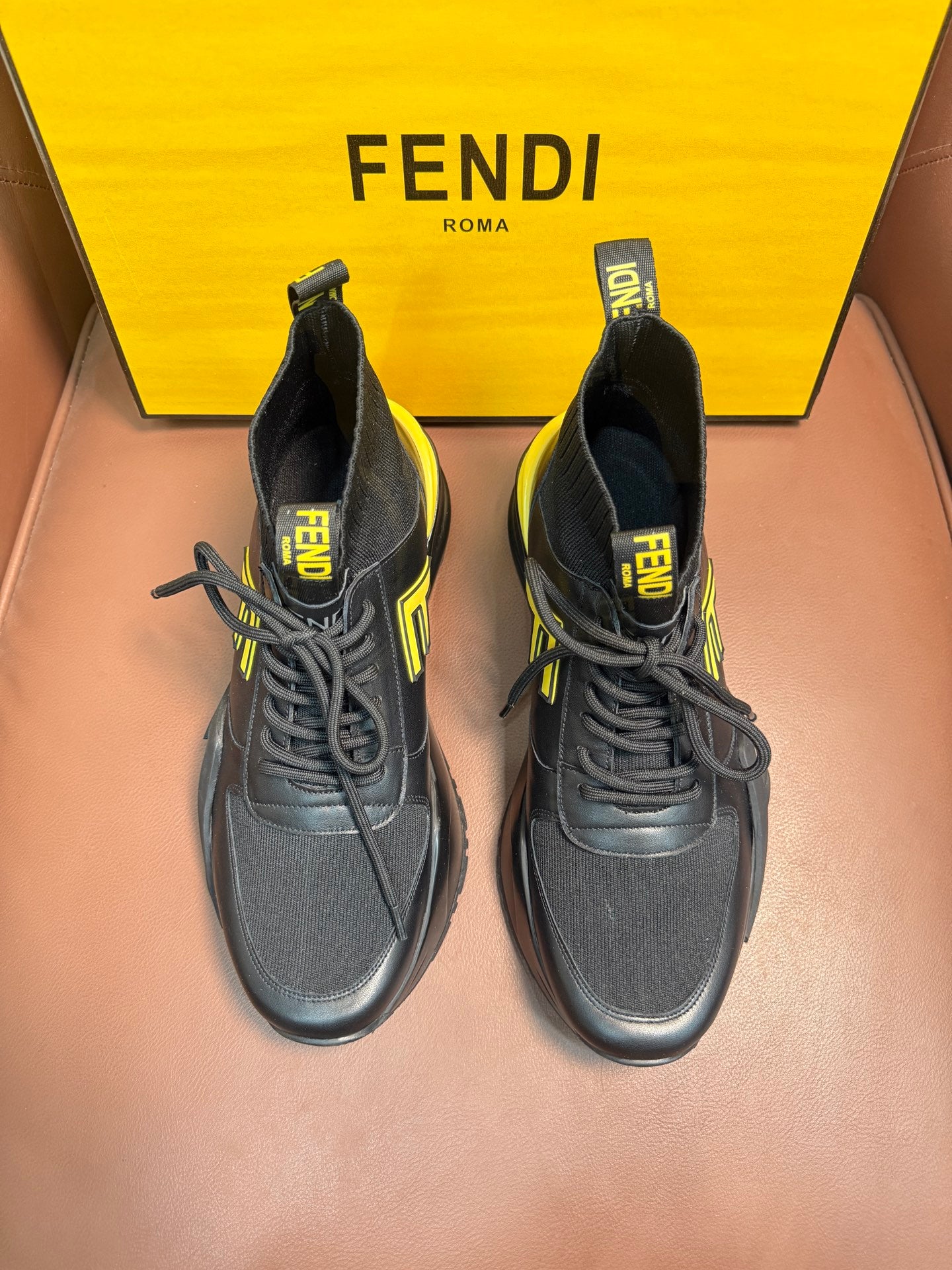 Pair of high-top sneakers in dark gray with neon yellow logo accents and chunky sole
