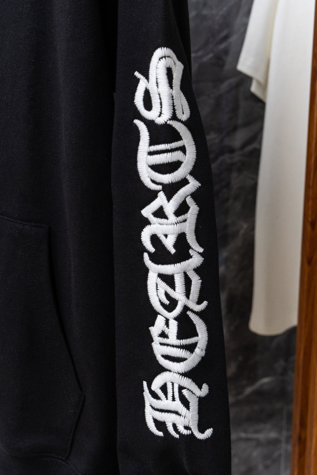 Black hoodie sleeve with large white graphic embroidery