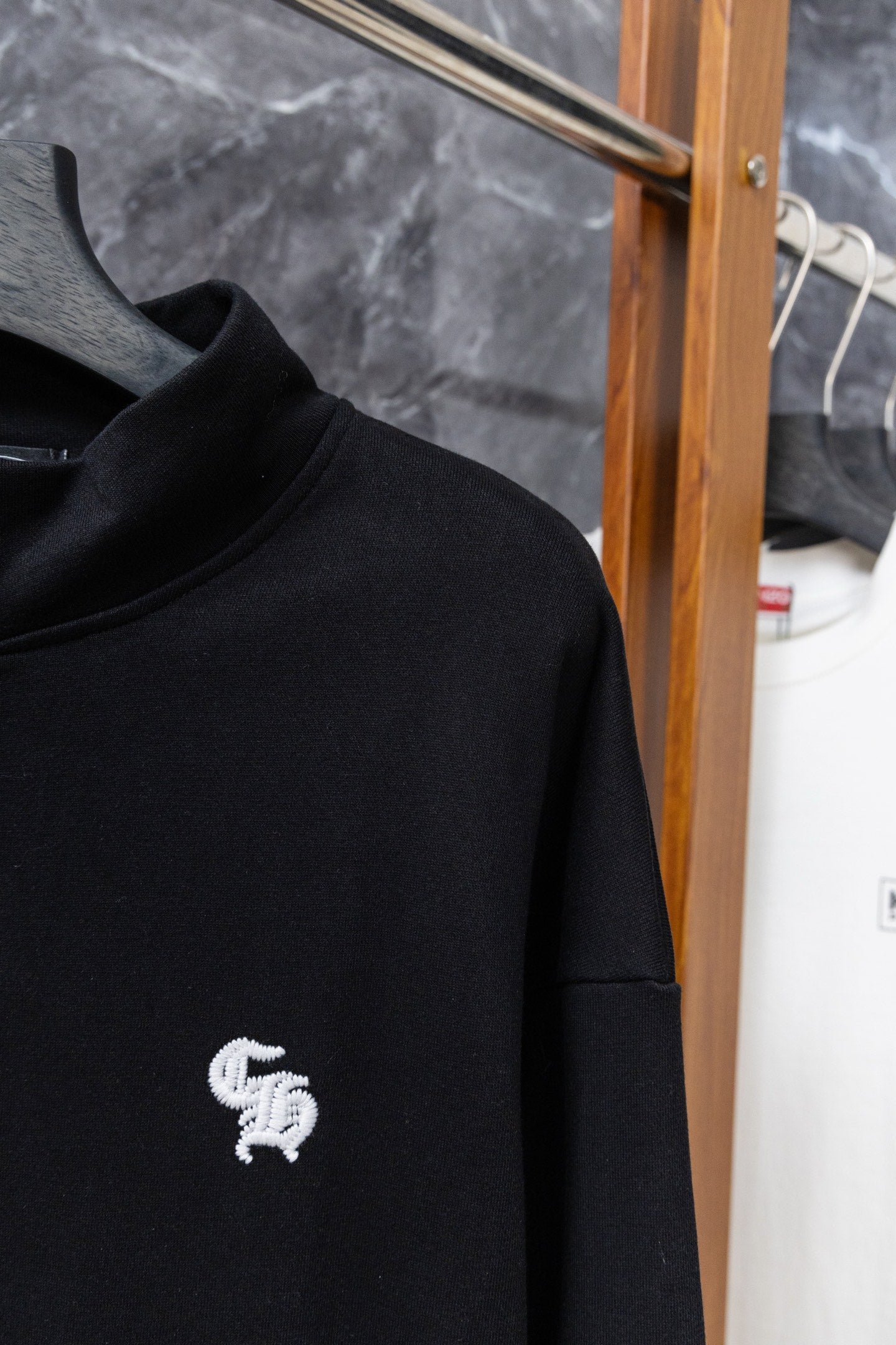 Black hoodie close-up of collar with small white chest logo