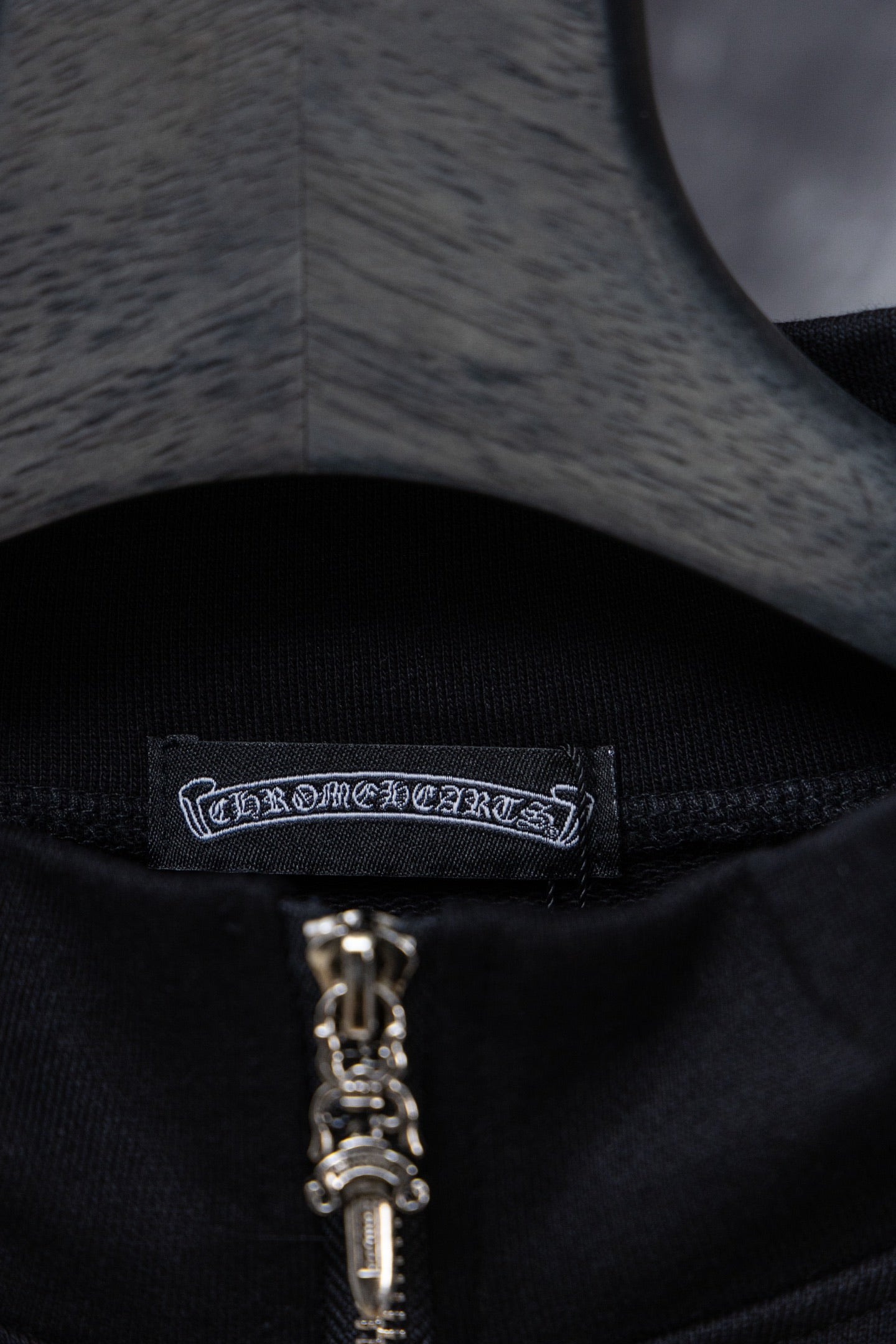 Black hoodie neckline with brand label and silver zipper pull