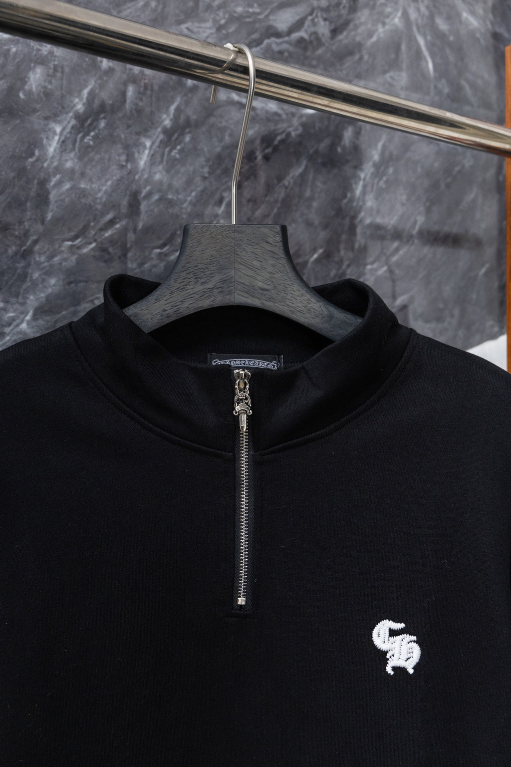Black zip-up hoodie front with silver zipper and small white chest logo