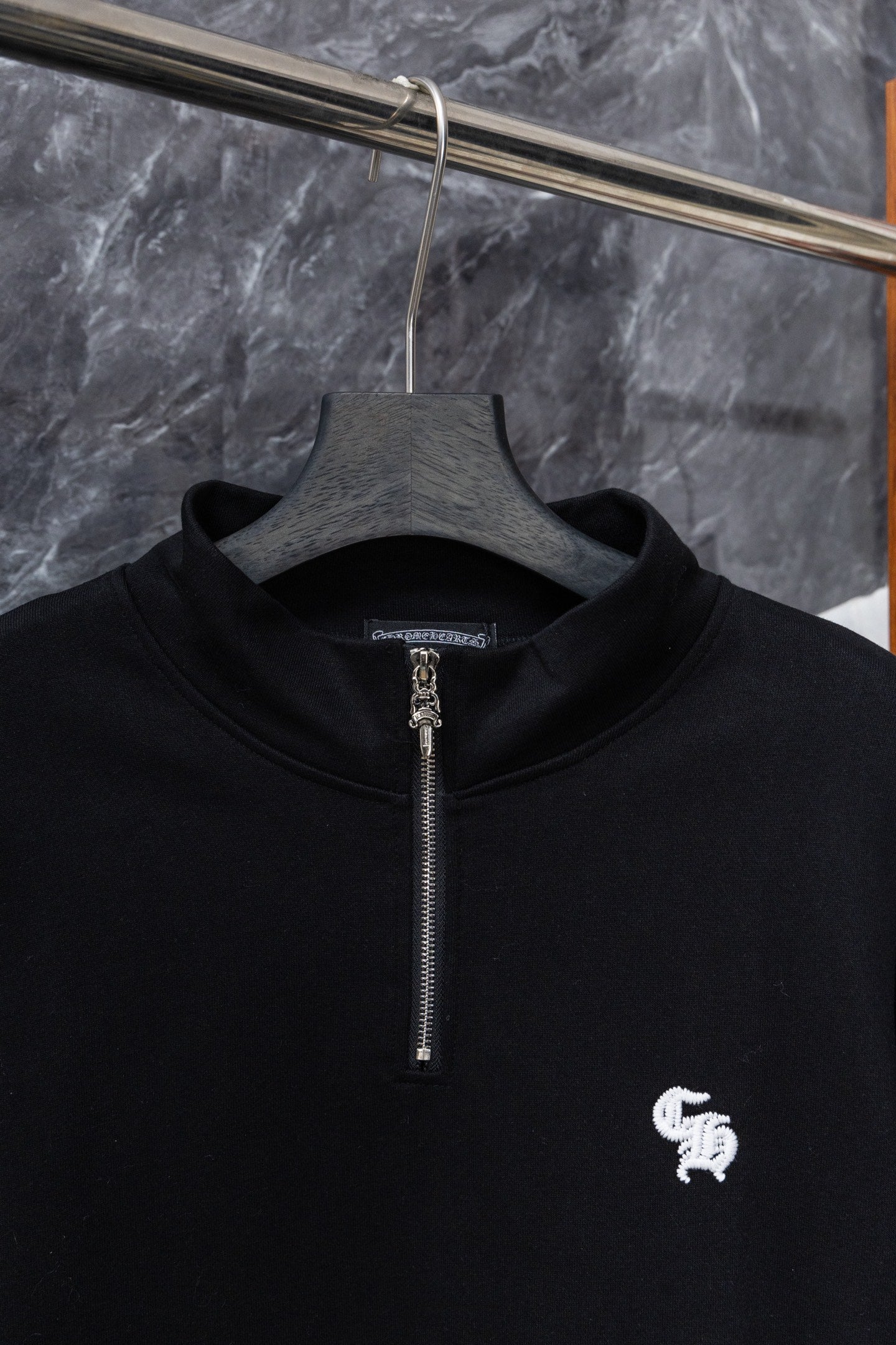 Black zip-up hoodie front with silver zipper and small white chest logo