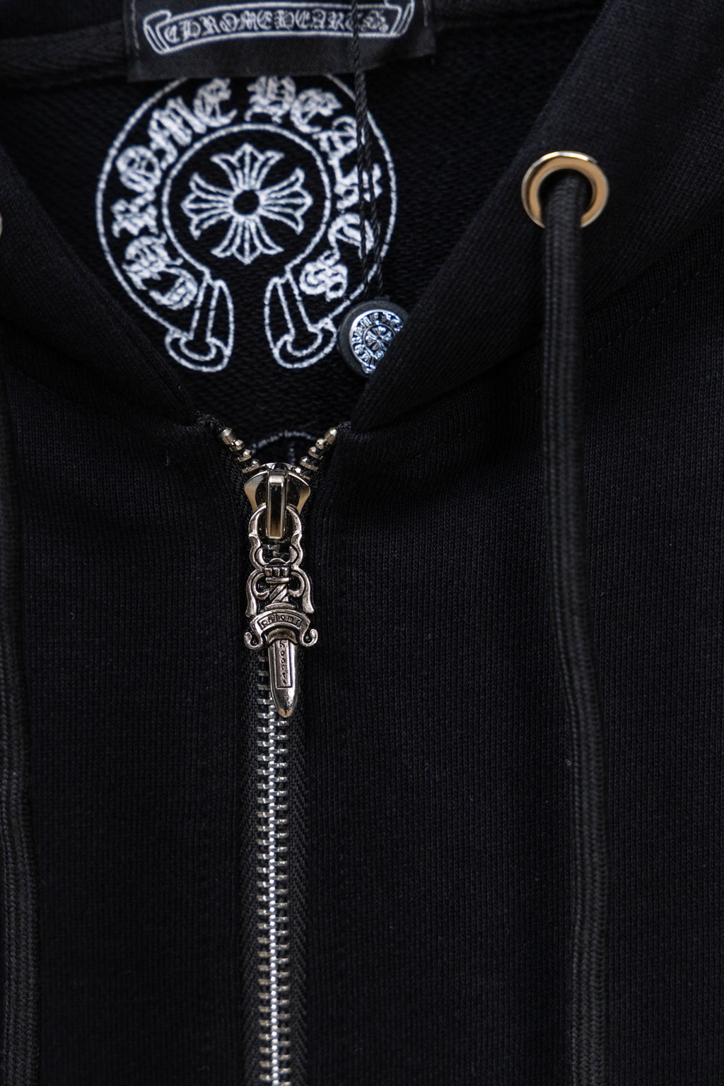 Black hoodie zipper close-up with decorative emblem on chest