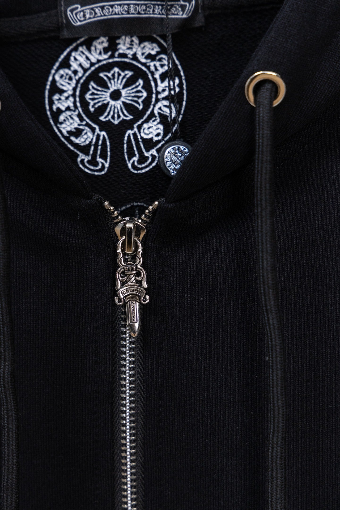Black hoodie zipper close-up with decorative emblem on chest