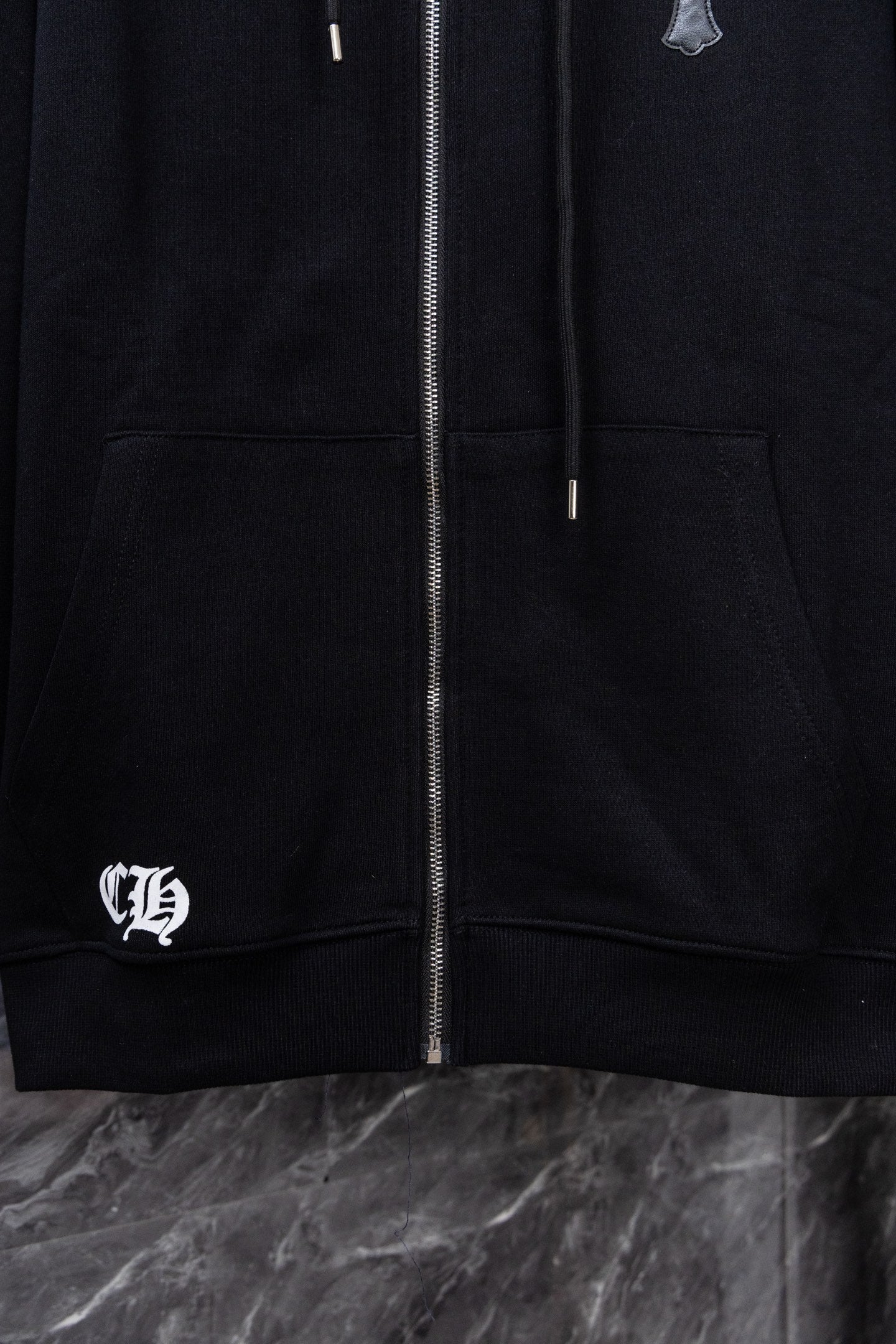 Black zip-up hoodie with front zipper, kangaroo pocket, and left chest logo