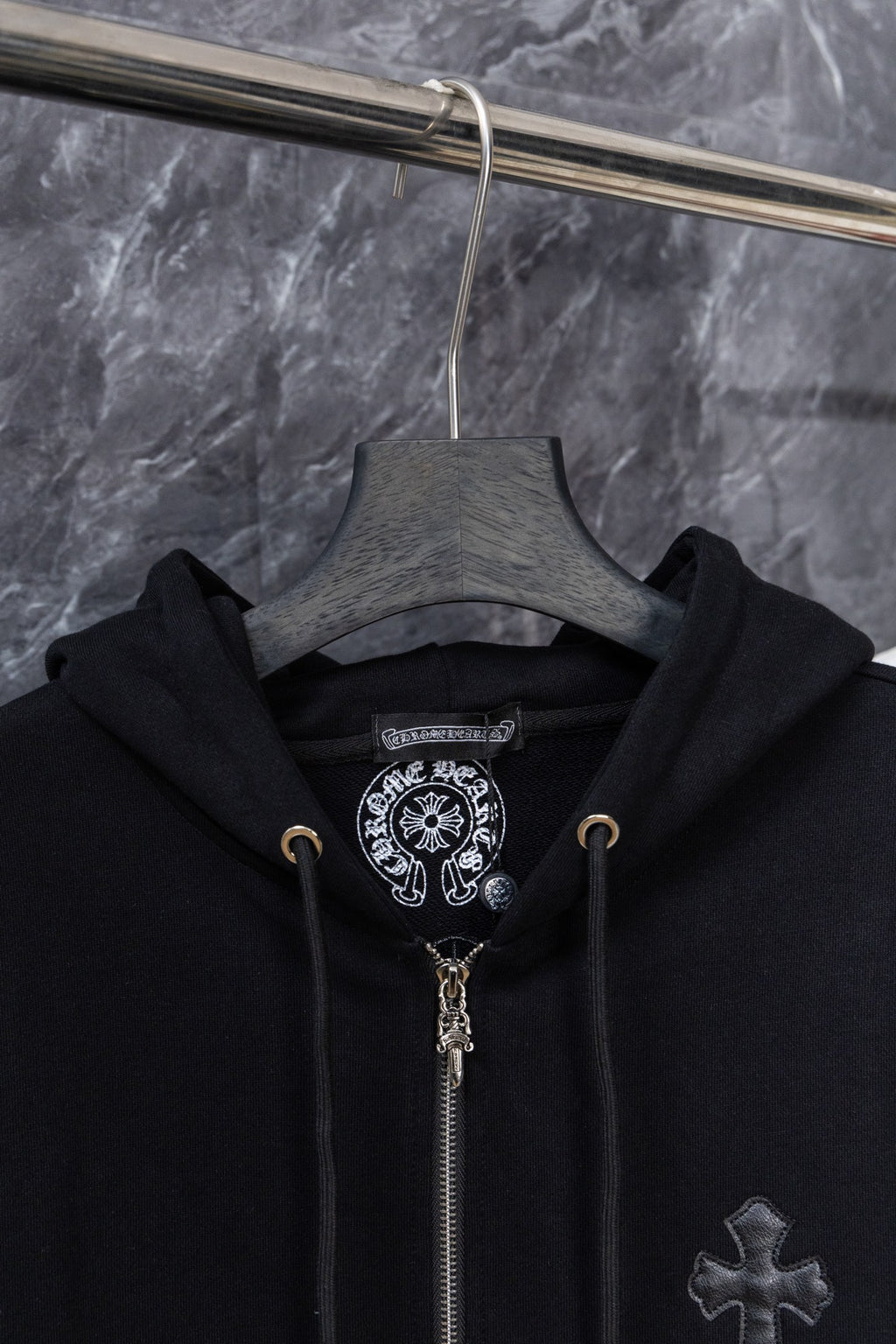 Black zip-up hoodie on hanger with hood and cross front embroidery