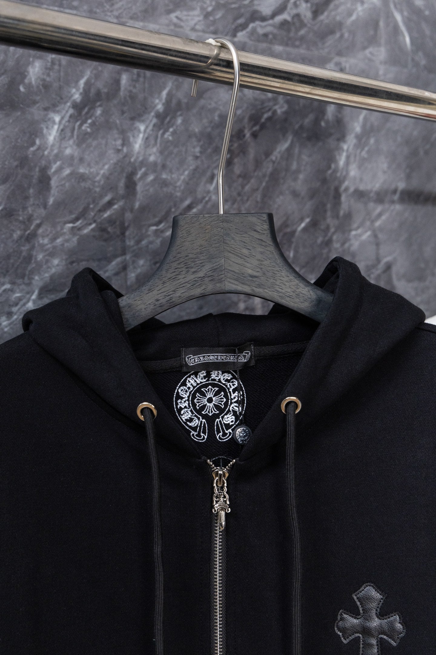 Black zip-up hoodie on hanger with hood and cross front embroidery