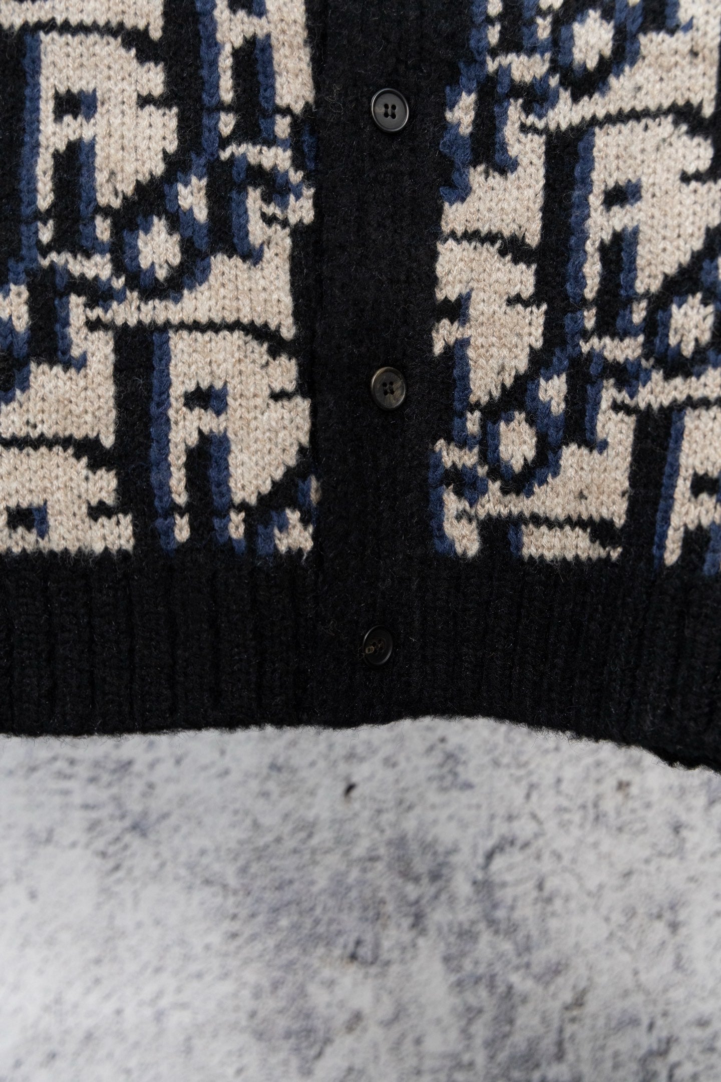 Knit cardigan front with black ribbed hem and navy/cream geometric jacquard