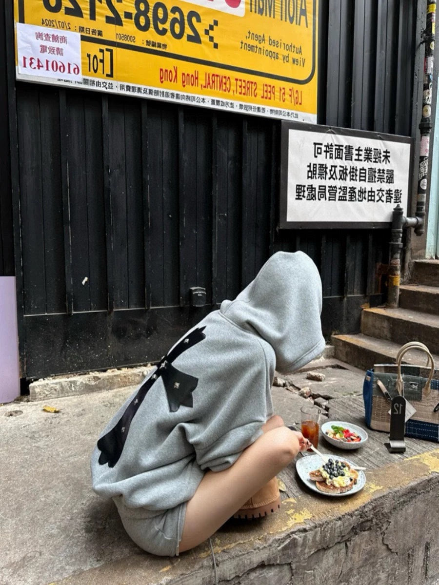 Gray hoodie with black bow-tie accents, hood up on model