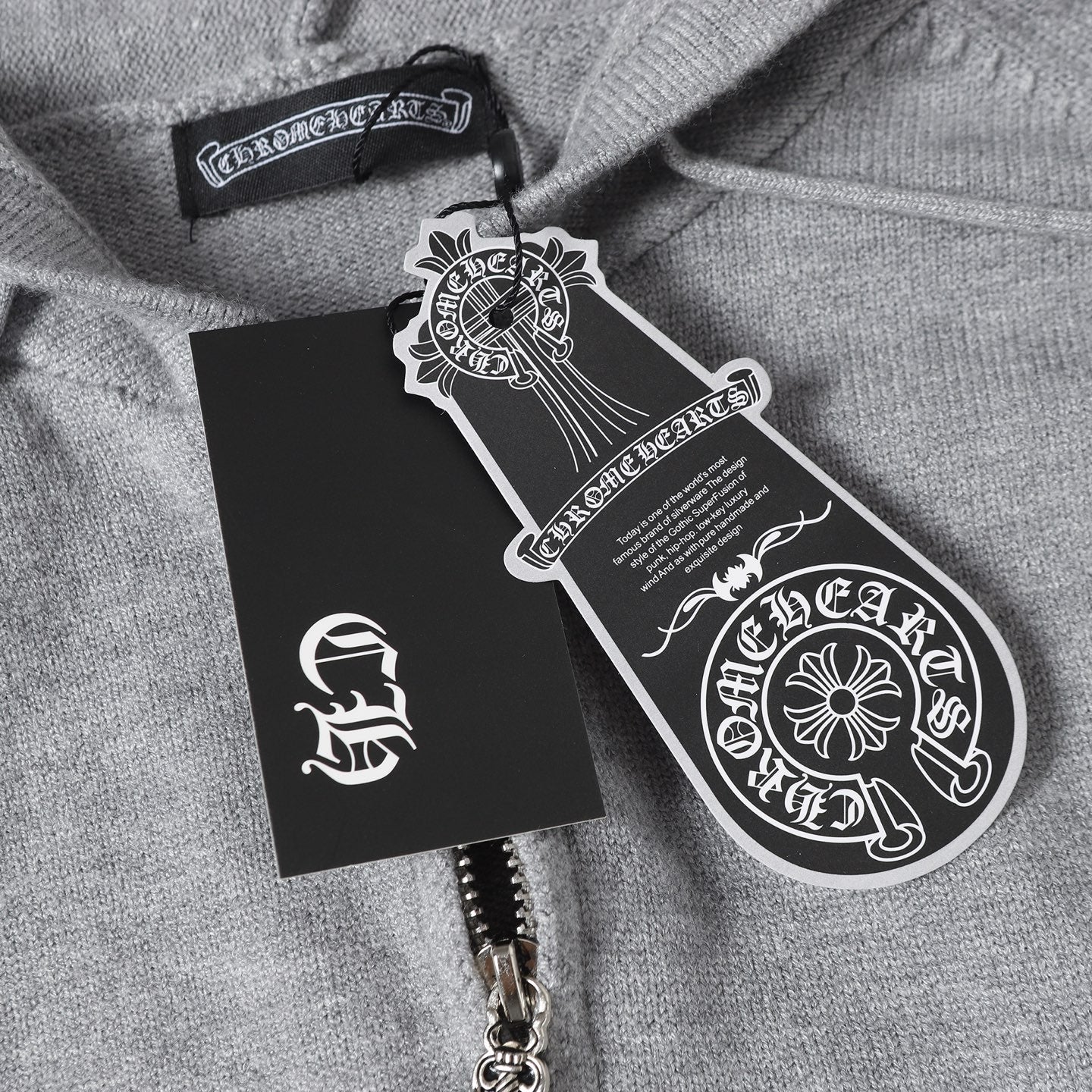 Light gray hoodie with black hang tag and product label near the zipper