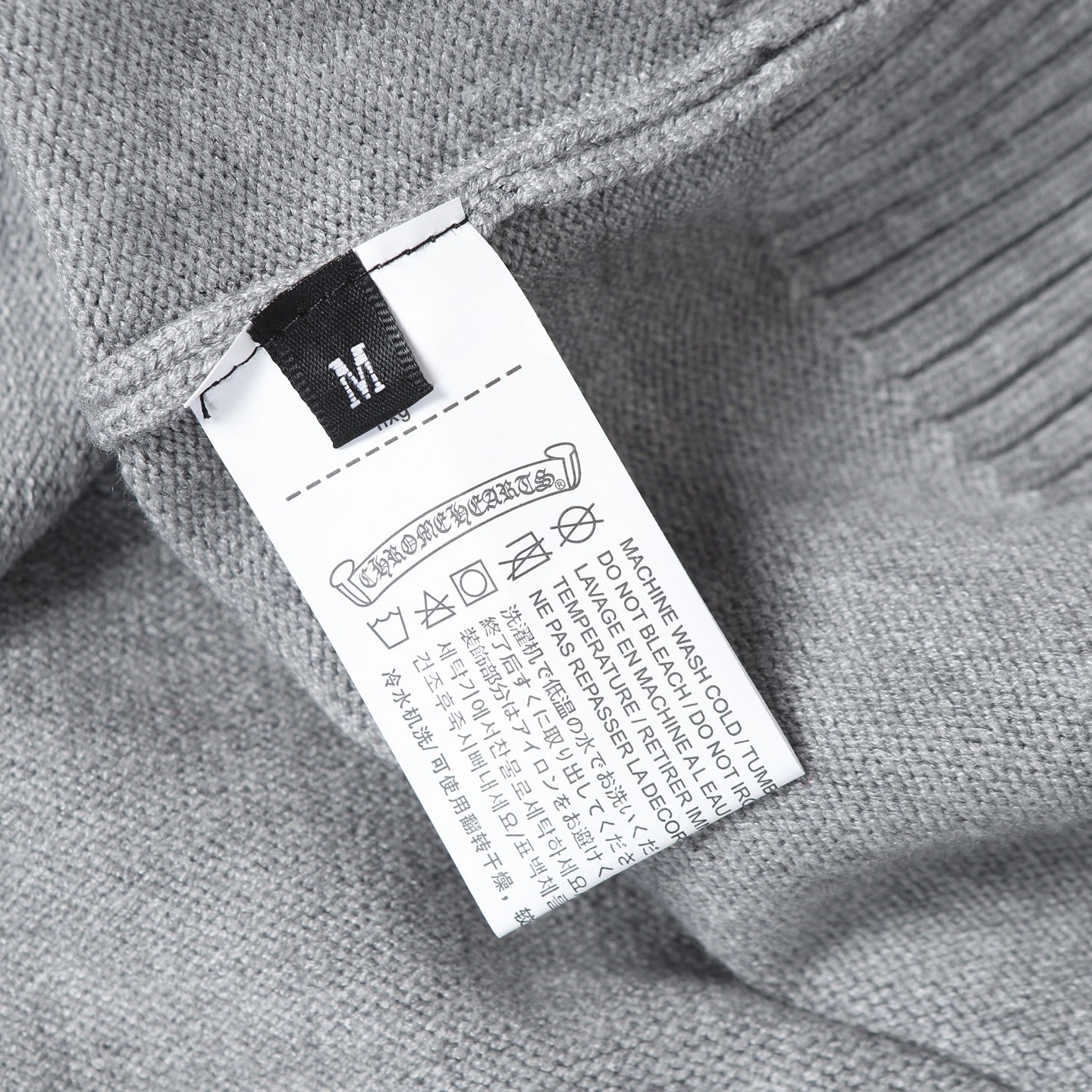 Light gray hoodie size and care label with icons and M size marker