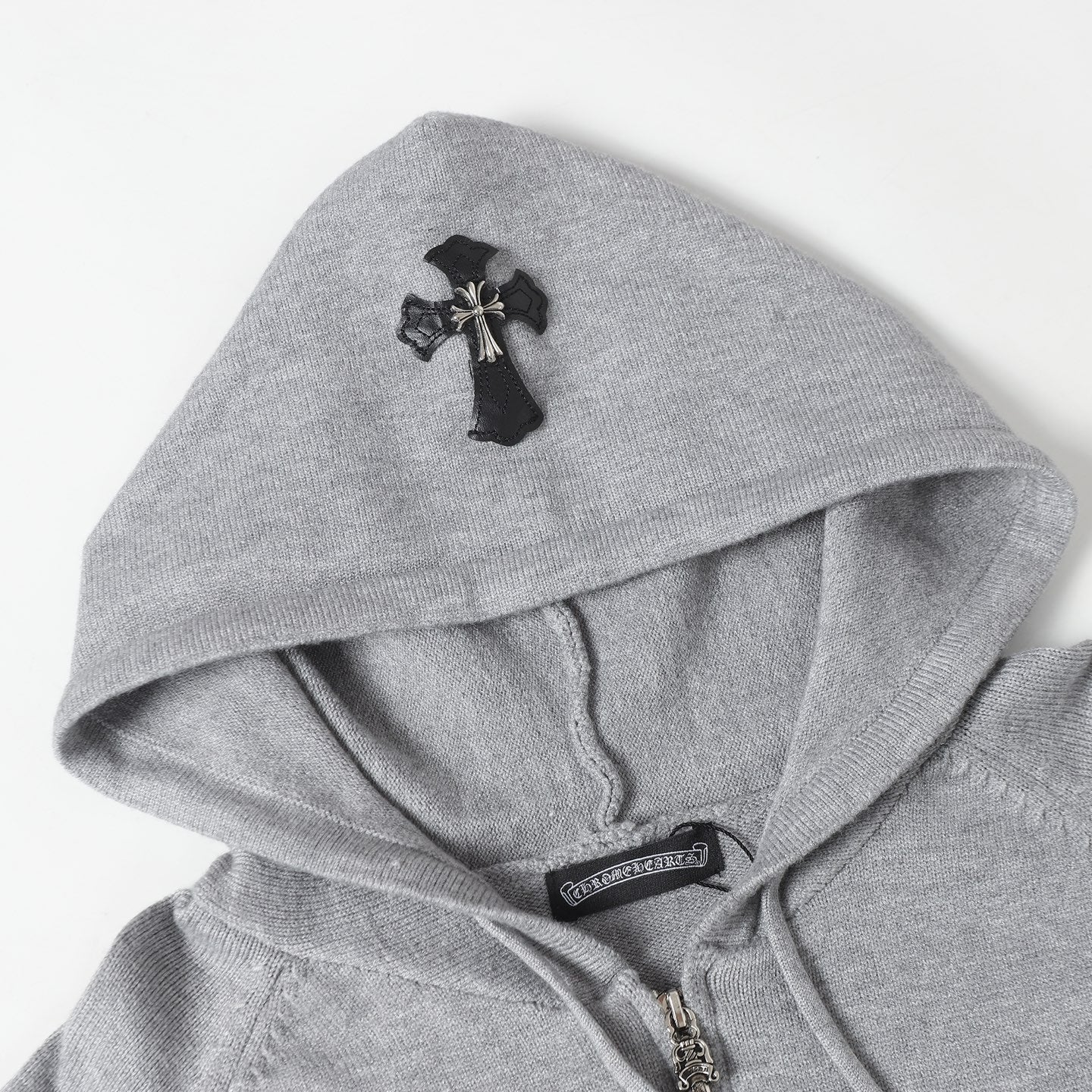 Light gray hoodie hood with black cross emblem and drawstring cords