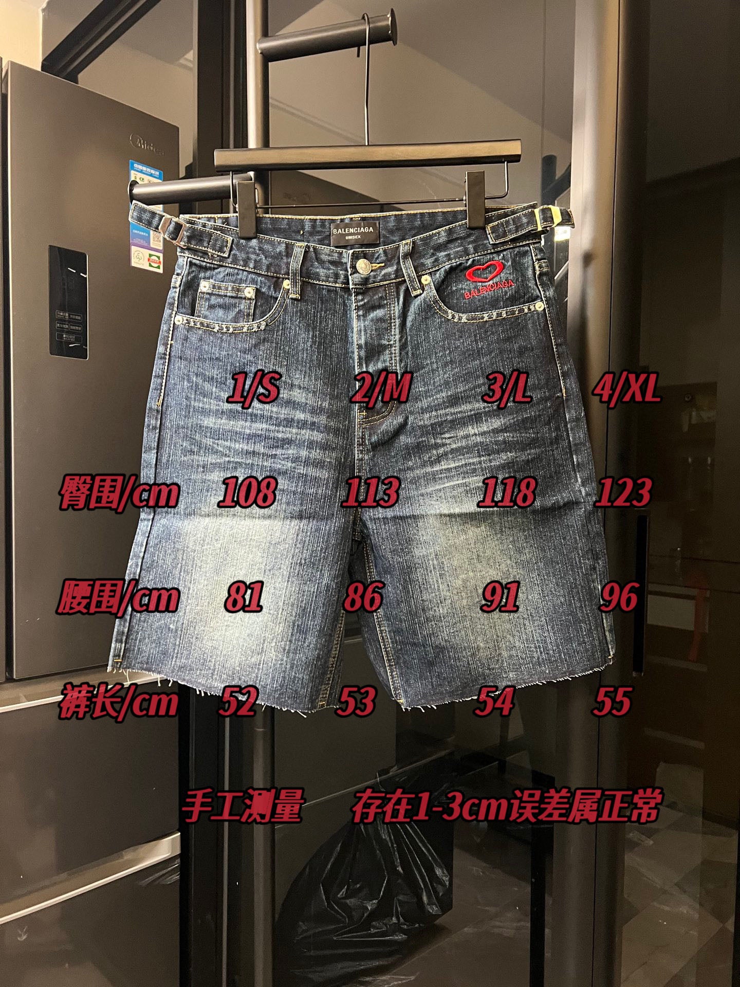 Balenciaga denim shorts on rack with red logo heart and sizing measurement overlay