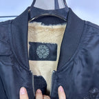 Long-sleeve bomber jacket interior with beige sherpa lining and blue logo label