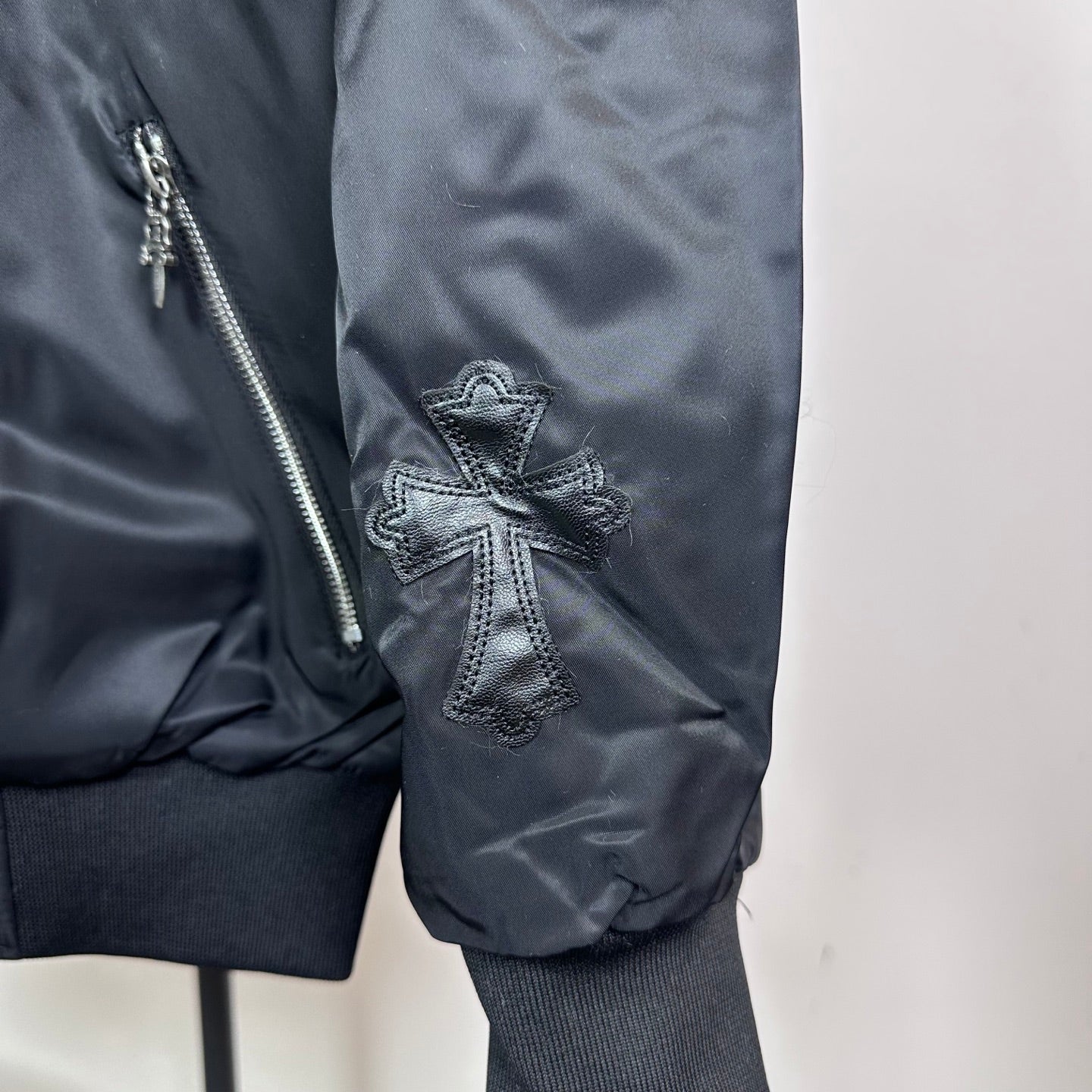 Dark blue bomber jacket side pocket with zipper and cross stitched patch on sleeve