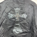 Long-sleeve jacket back featuring large stitched cross emblem on satin surface