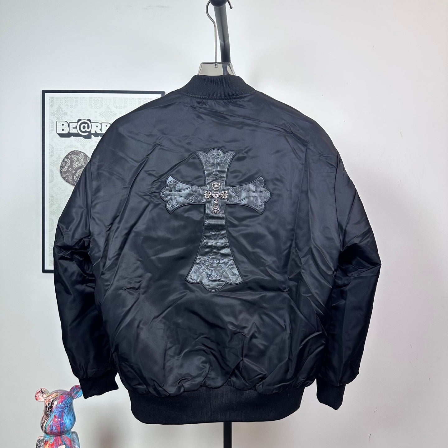 Dark blue bomber jacket back view with large cross emblem and ribbed hem