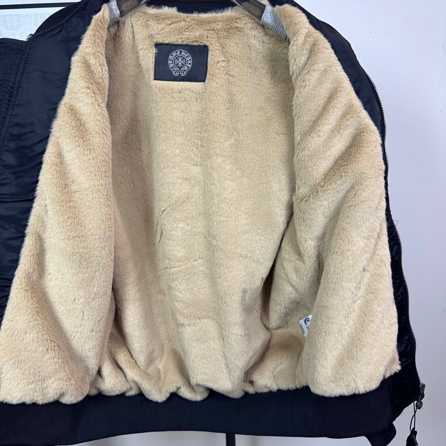Long-sleeve jacket lining in beige sherpa with blue brand patch at chest
