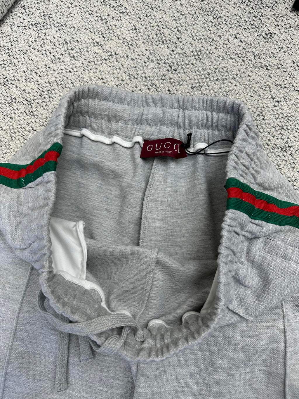 Gray Gucci pants with elastic waistband, drawstring, and red/green web stripe