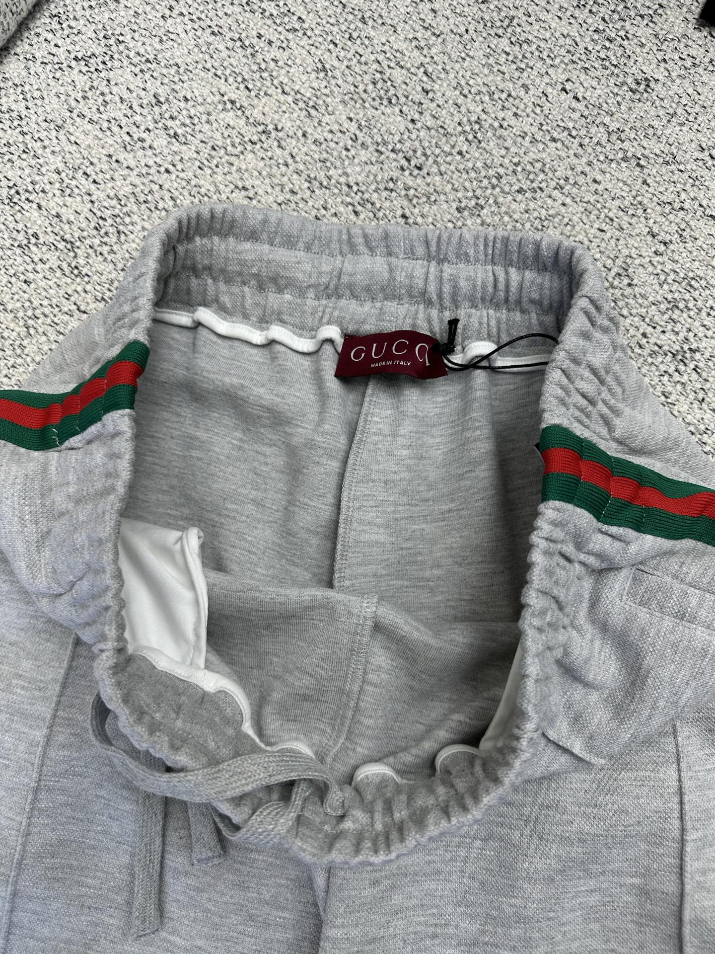 Gray Gucci pants with elastic waistband, drawstring, and red/green web stripe