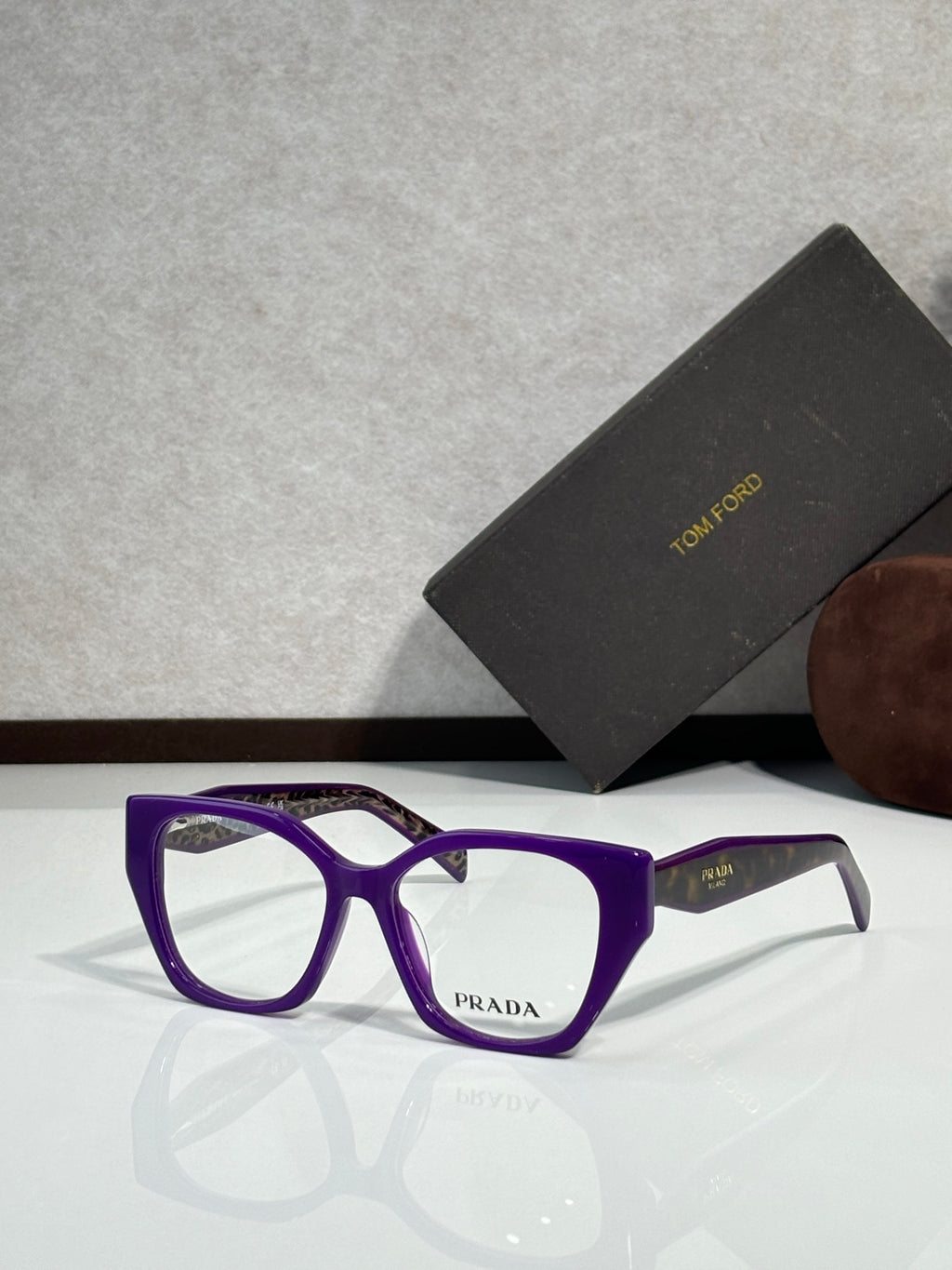 Prada eyeglass frames with purple acetate front and clear lenses, Prada logo at center.