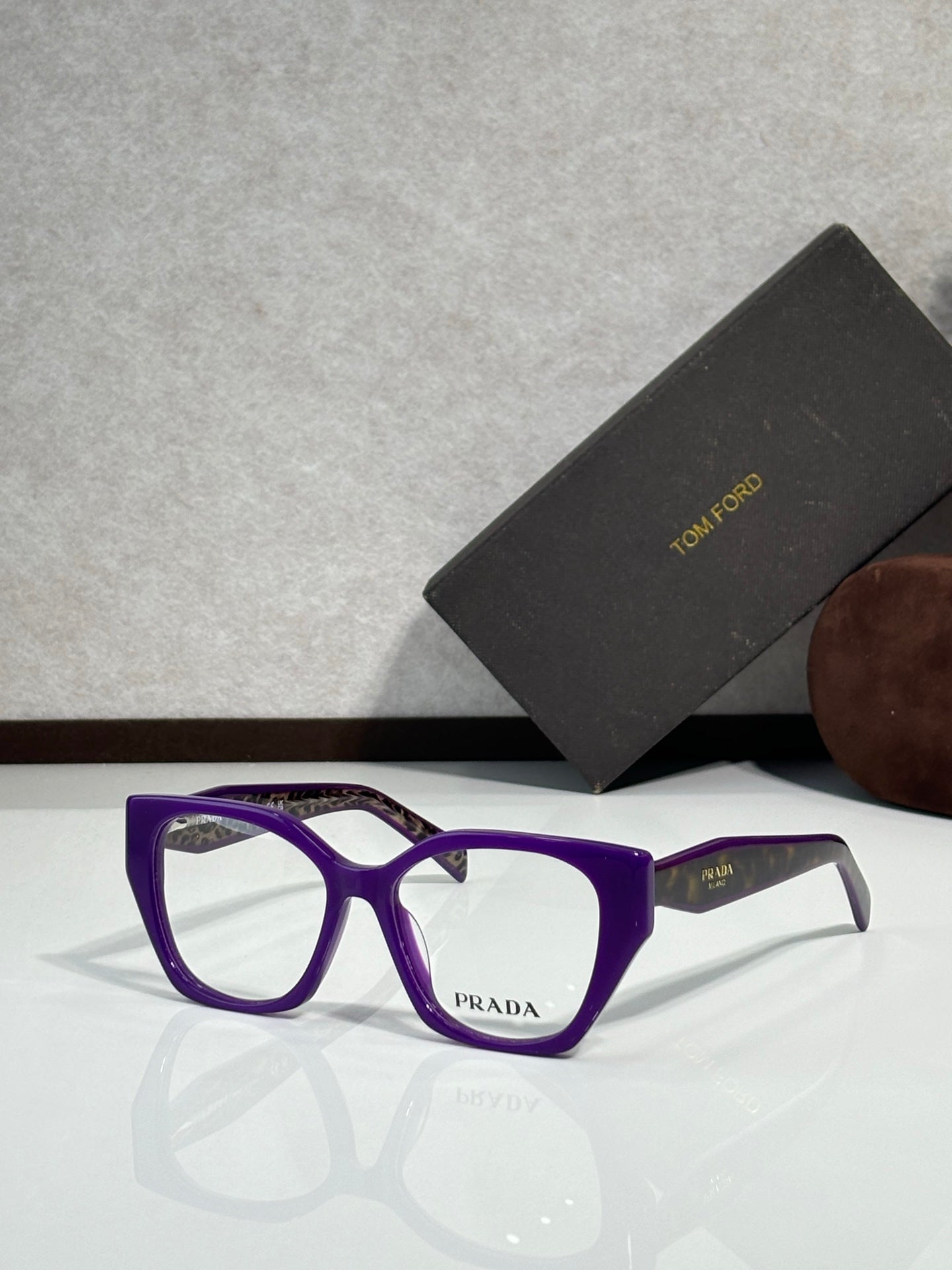 Prada eyeglass frames with purple acetate front and clear lenses, Prada logo at center.