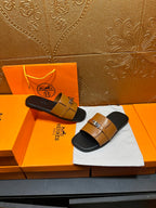 Tan leather slide sandals with silver buckle straps on black footbeds