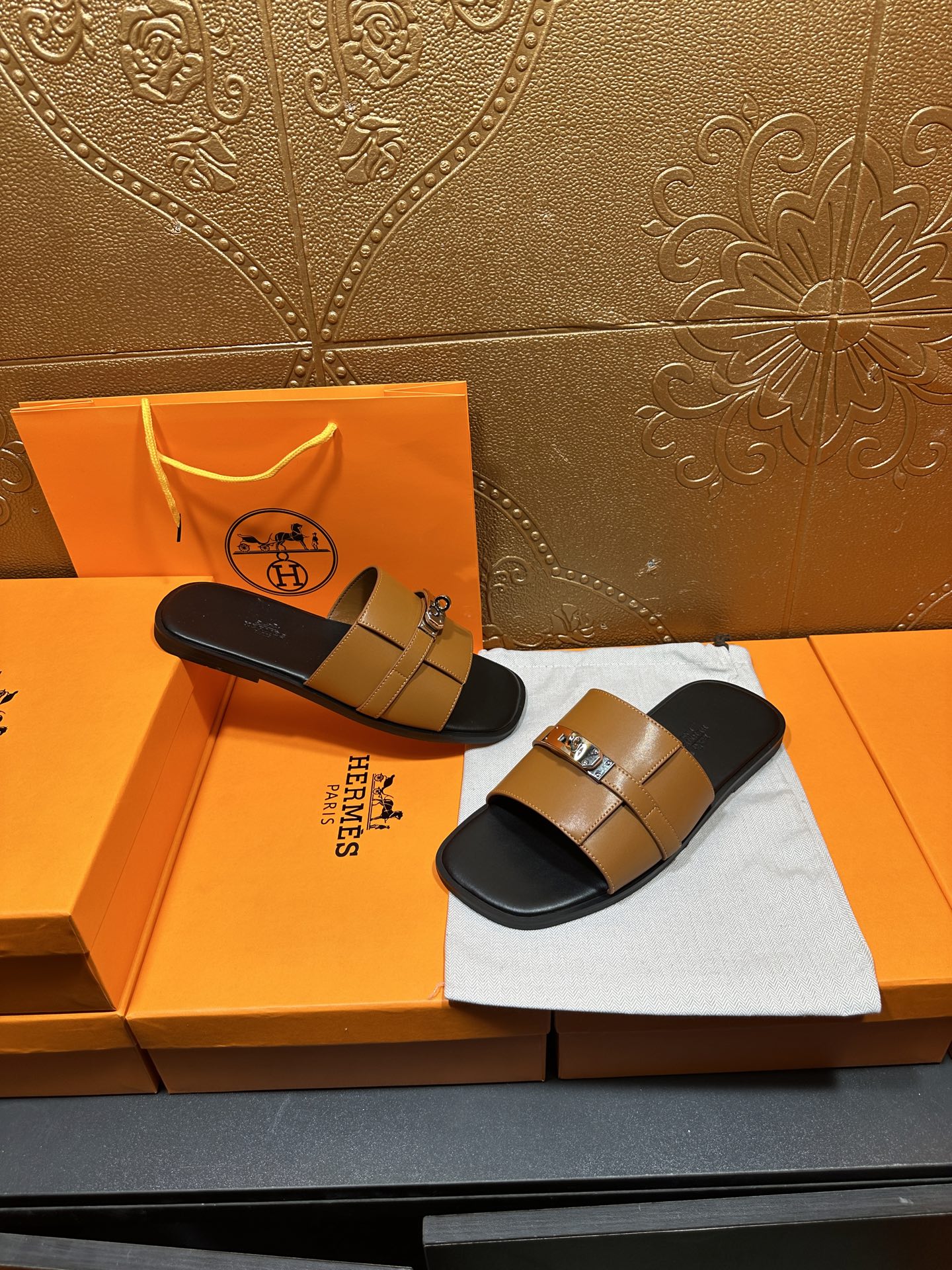 Tan leather slide sandals with silver buckle straps on black footbeds