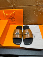Tan leather sandals with shiny buckle straps and black footbeds