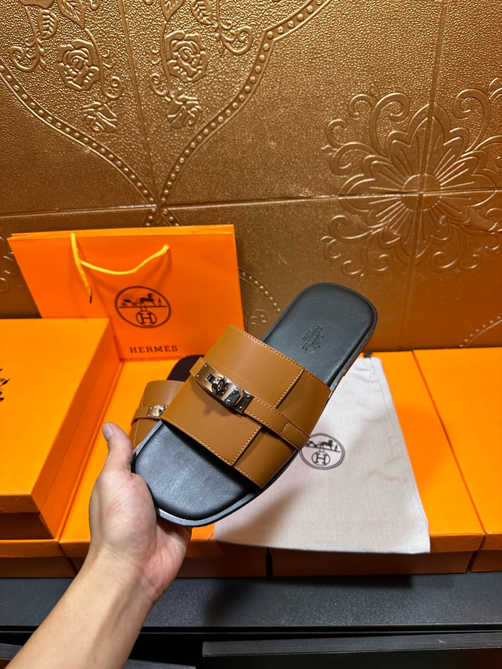 Tan leather slide sandal held up, with silver buckle strap and dark footbed