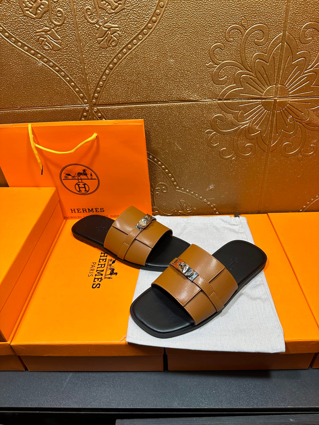 Tan leather slide sandals with silver buckle straps on black footbeds