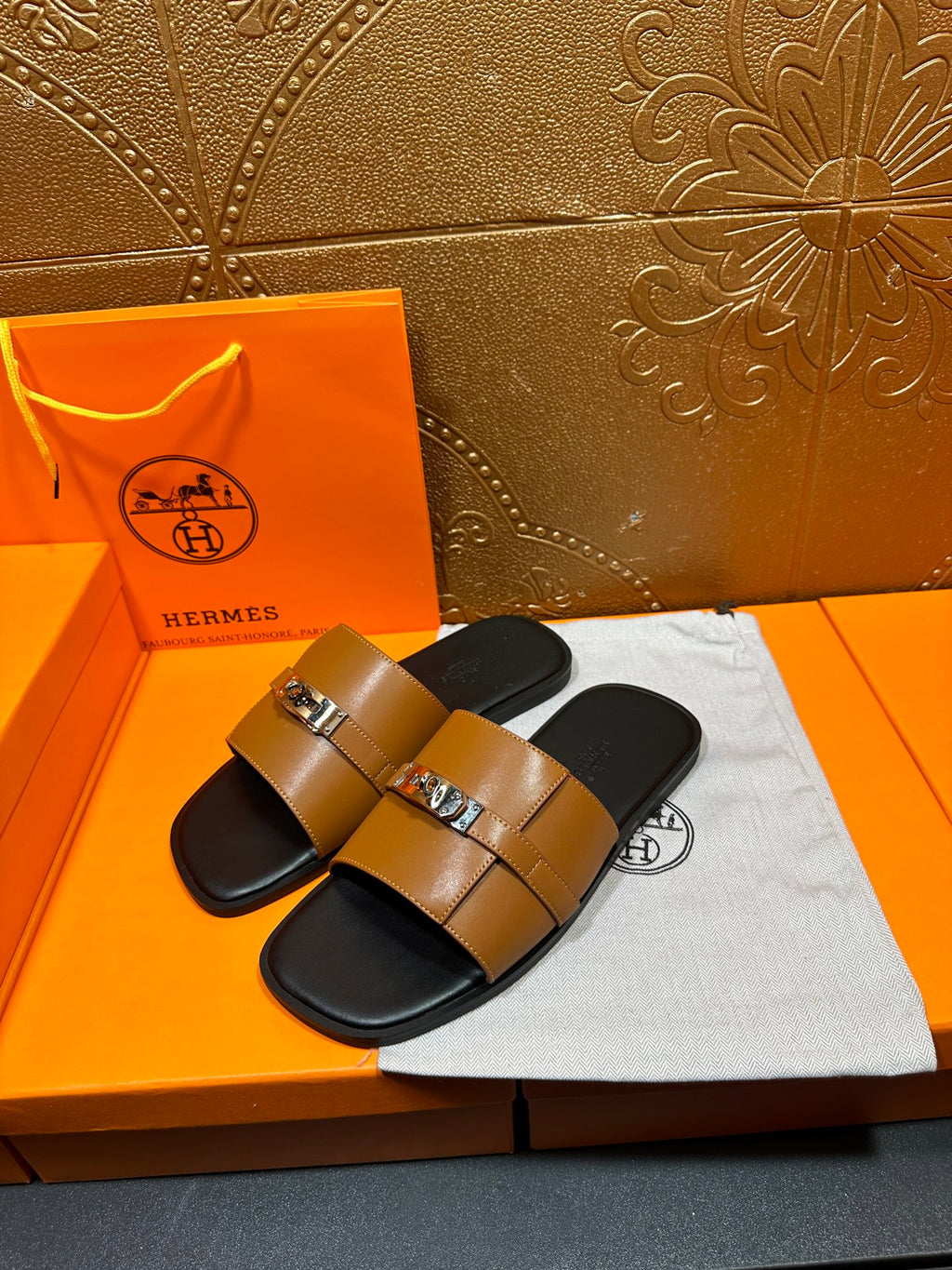 Tan leather slide sandals with silver buckle strap and black footbed
