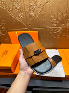 Tan leather slide sandal with silver buckle strap and dark footbed