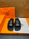 Hermes black leather slide sandals with wide strap and buckle detail
