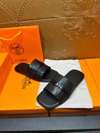 Hermes black leather slide sandals with wide strap and buckle, flat footbed