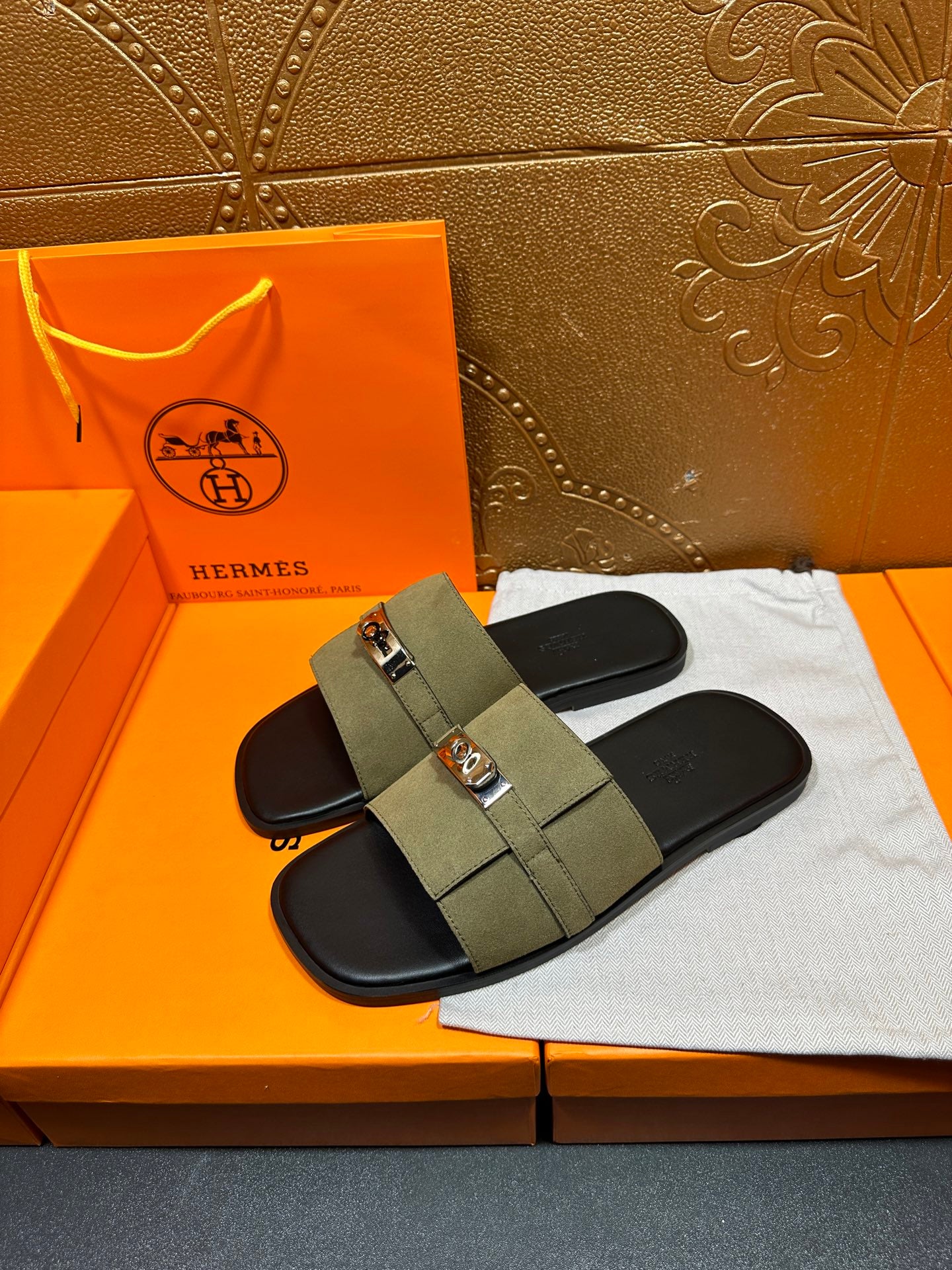 Pair of Hermes luxury slide sandals in olive green with silver buckle over black footbeds