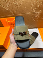 Hermes luxury slide sandals held in hand: olive green strap with silver buckle